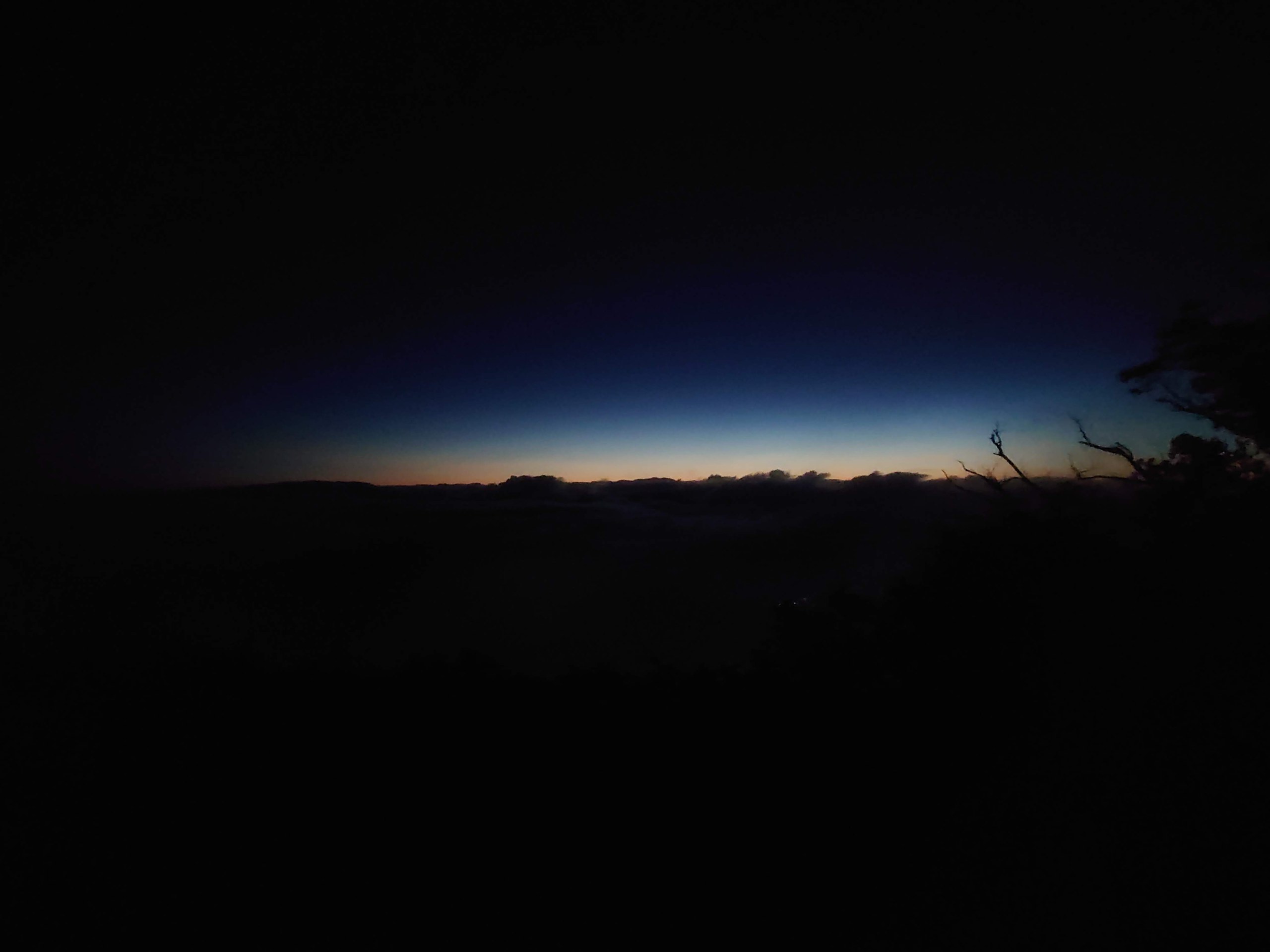 夜明け前の空と地平線のオレンジ色の光