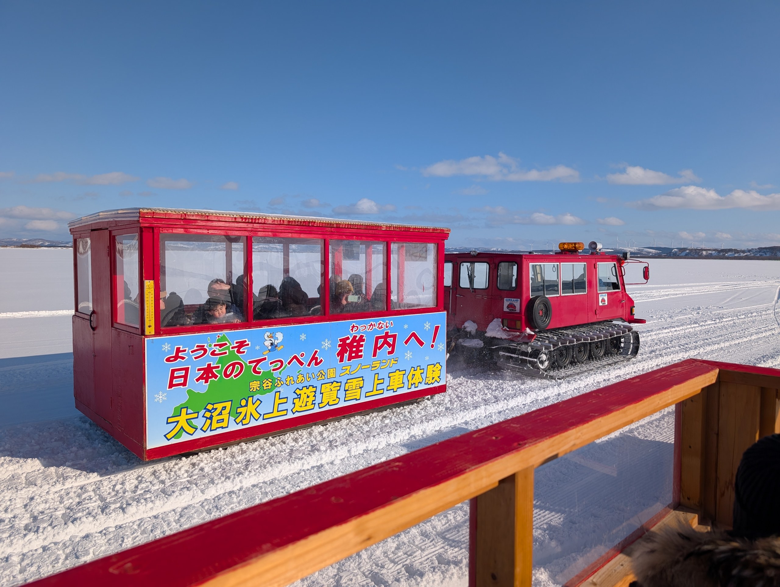 「大沼氷上遊覧雪上車」と書かれた、雪上車に引かれるそり