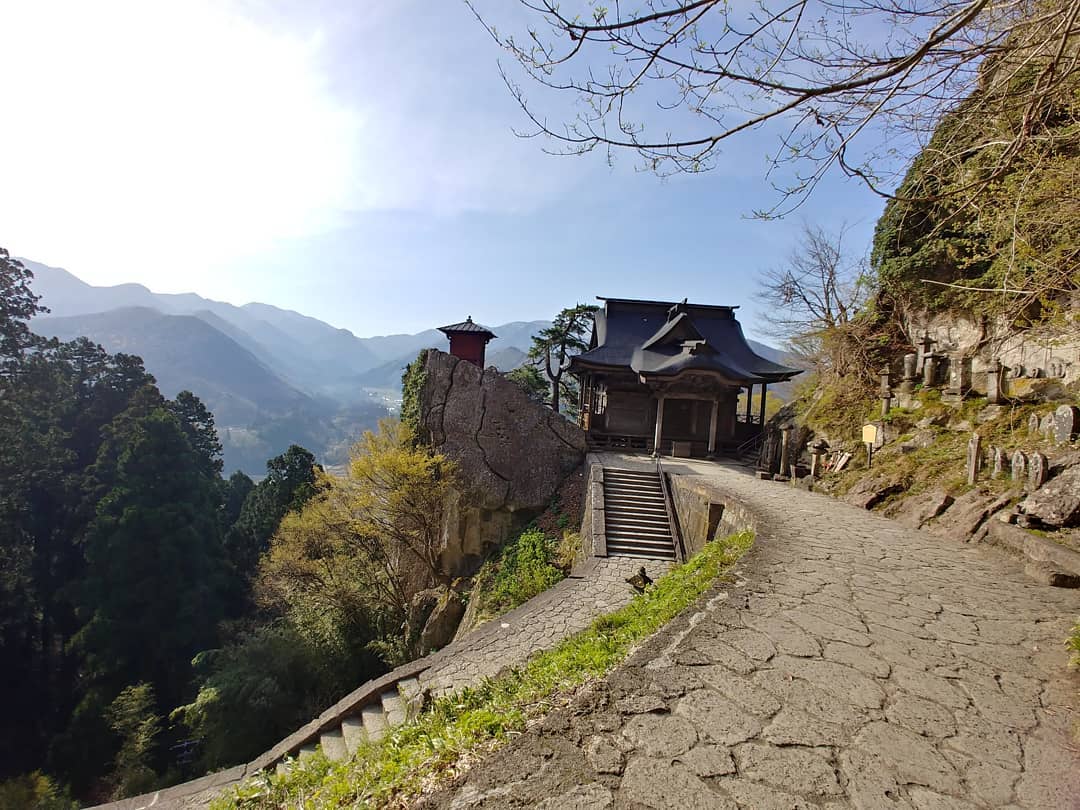岩山の上に建つ山寺のお堂と、谷あいの景色