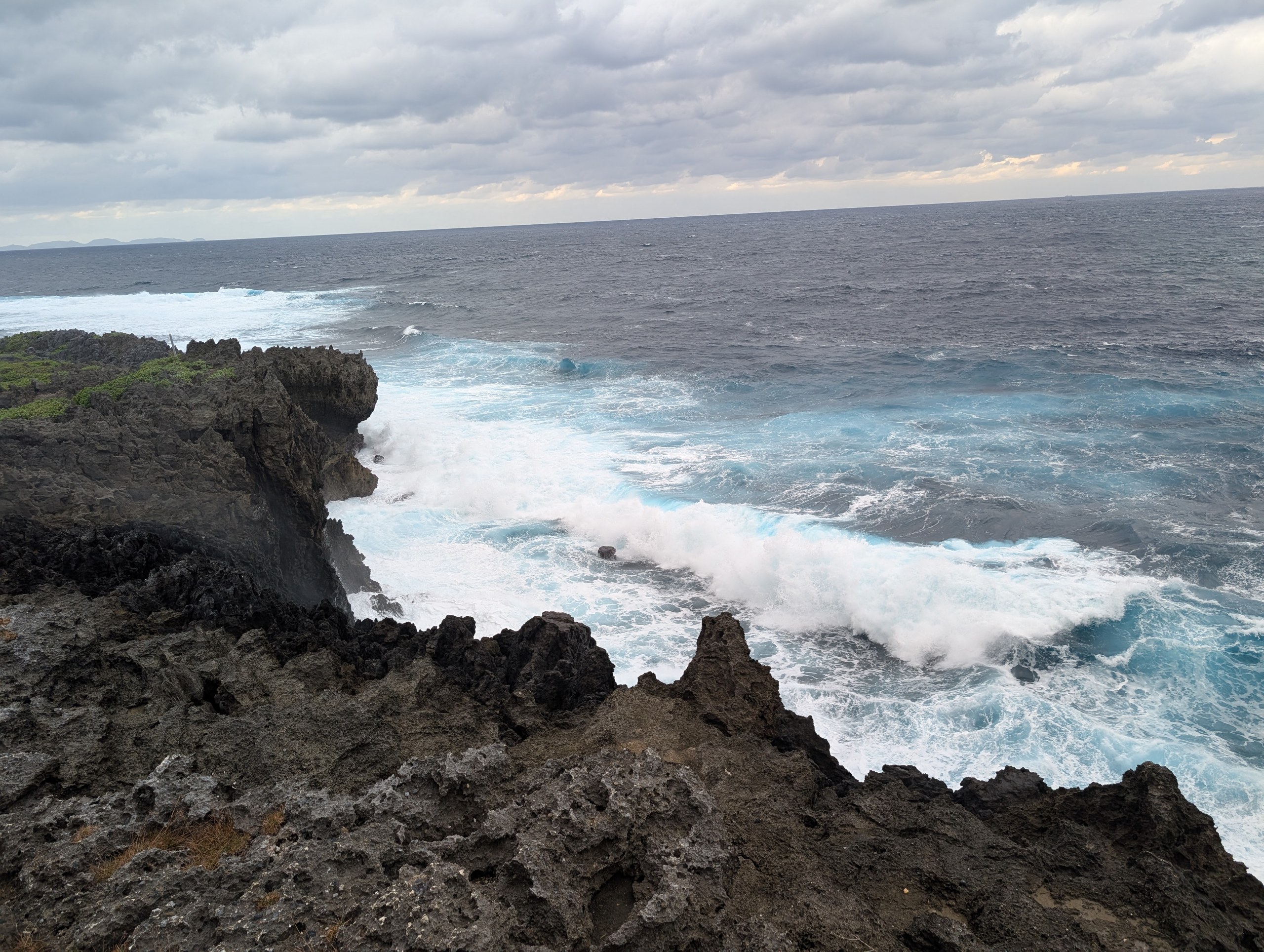 辺戸岬のごつごつした黒い岩に、白い波が打ち寄せる荒れた海