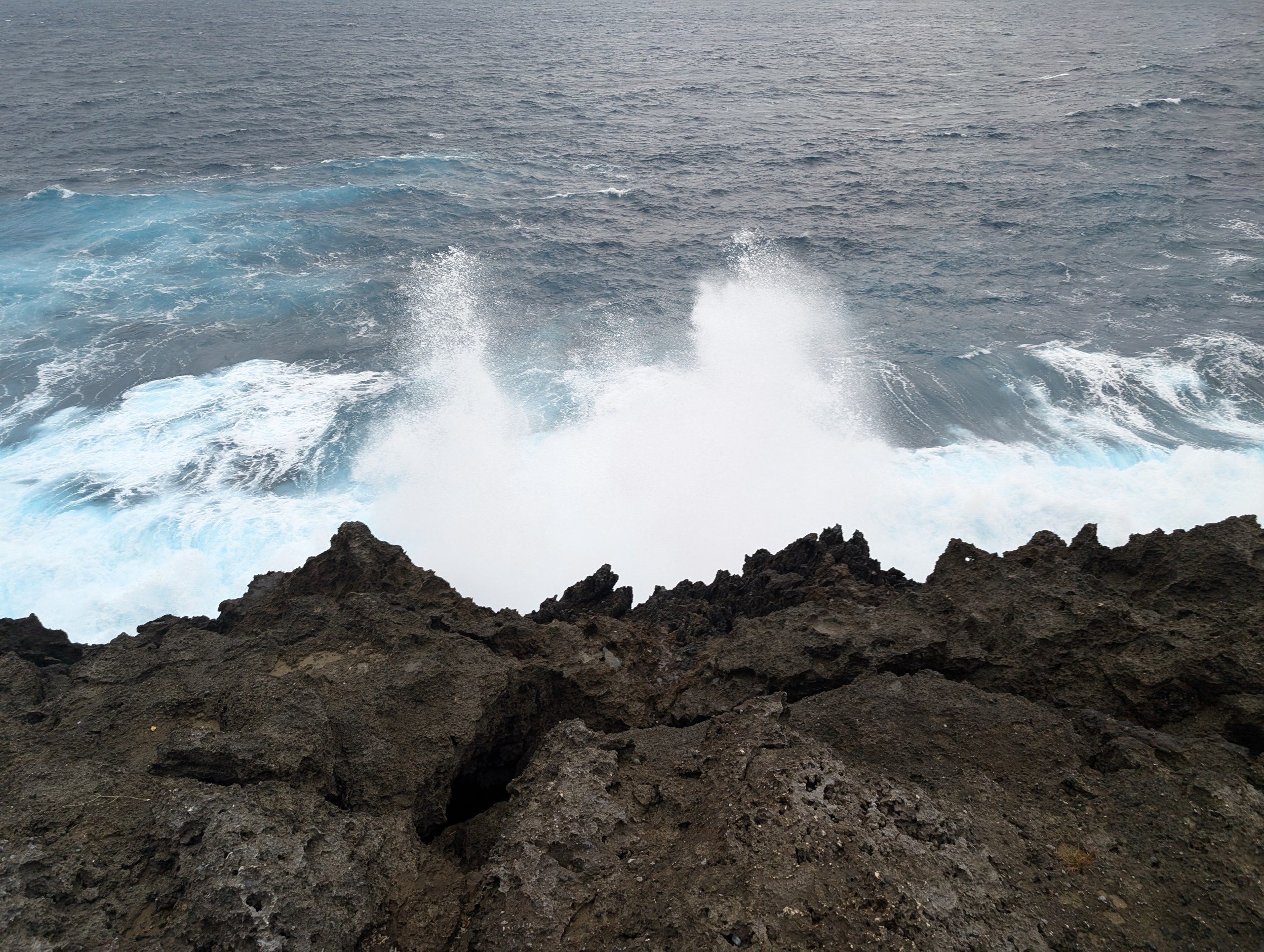 岩にぶつかって大きく砕け散る白い波しぶき
