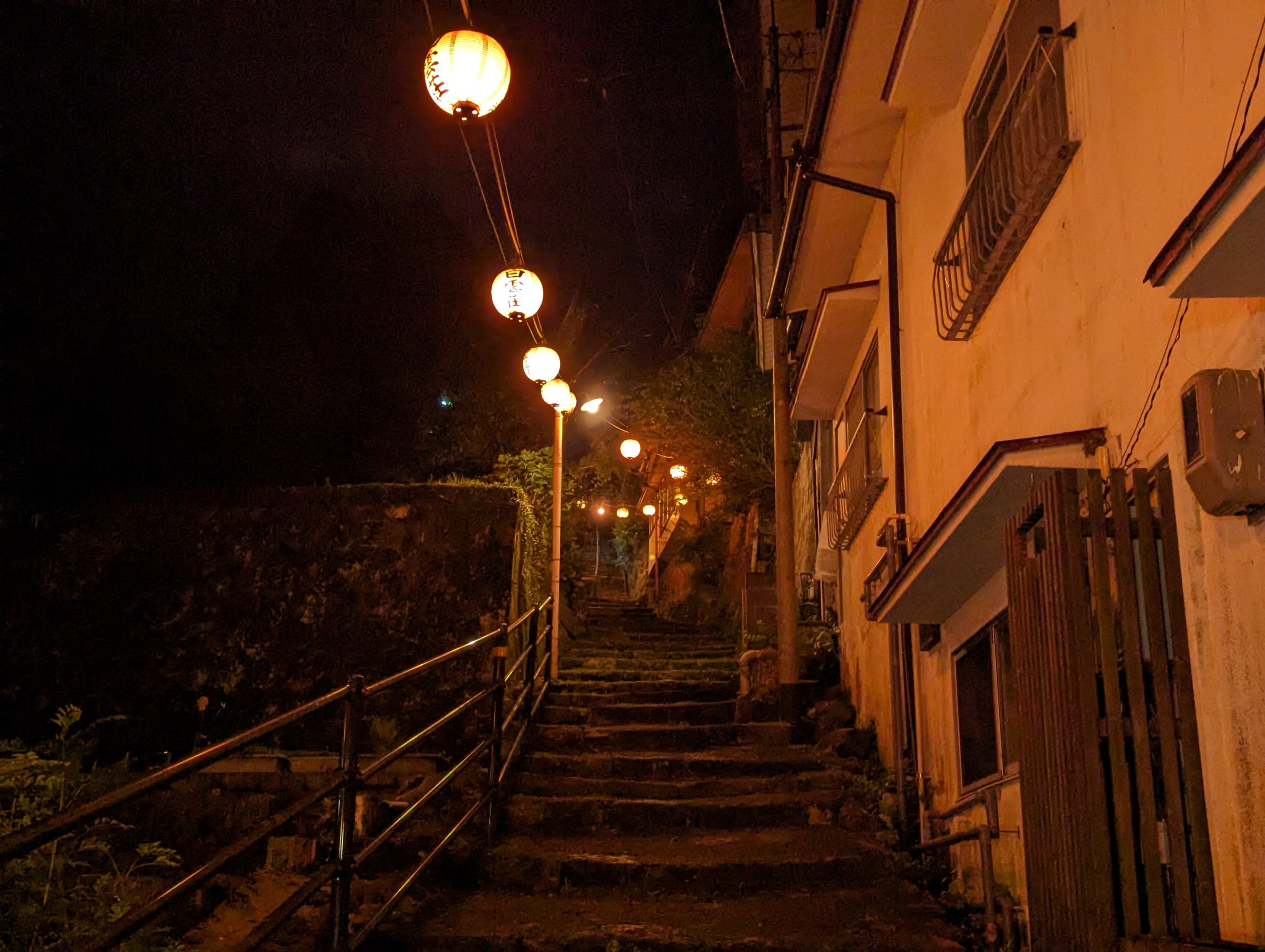 提灯が並ぶ石段を見上げた、夜の温泉街