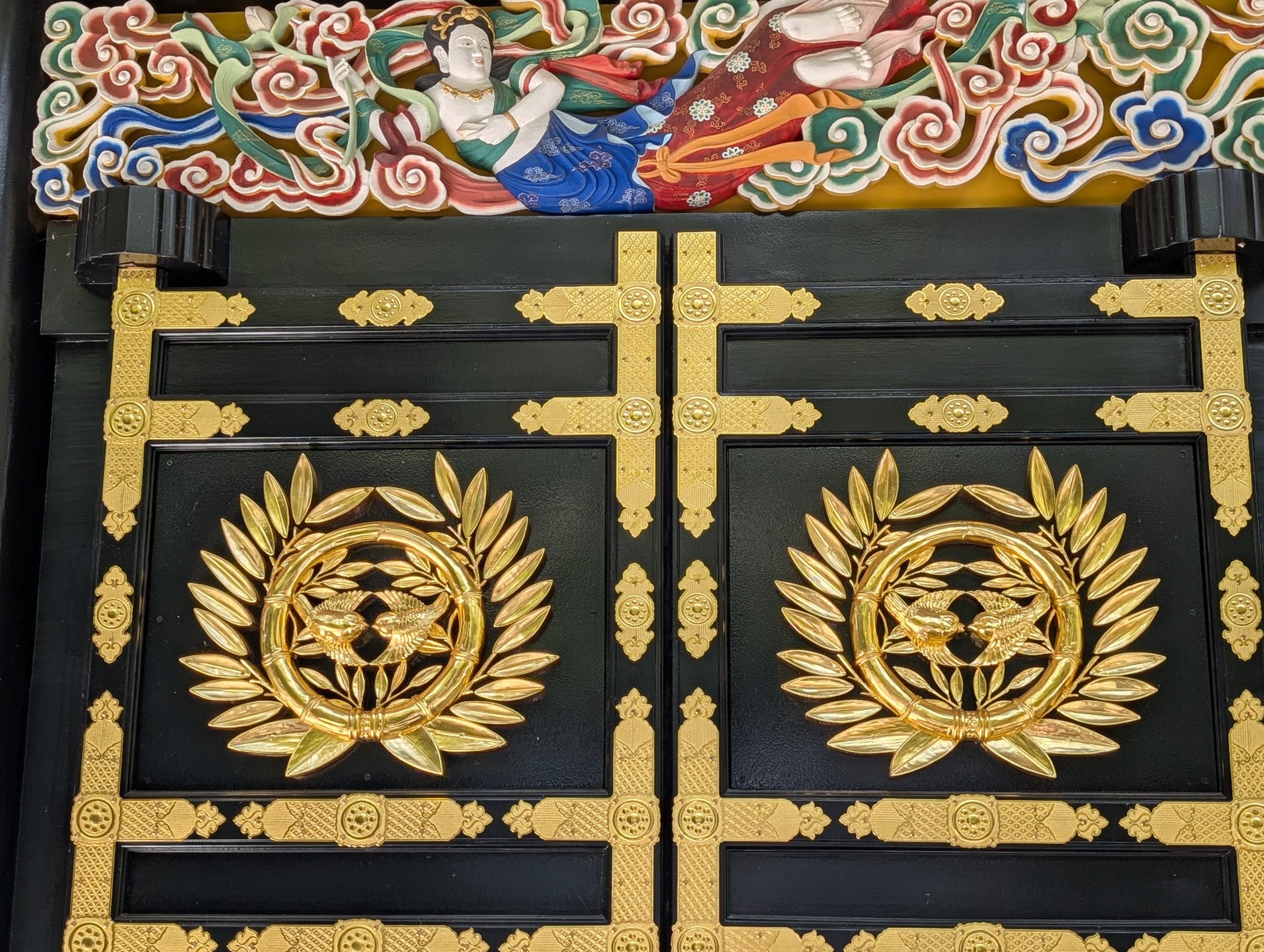 色鮮やかな彫刻の下の、金の紋の扉